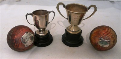 Lot 147 - Two leather cricket balls with silver presentation plaques. A small silver trophy cup and a...