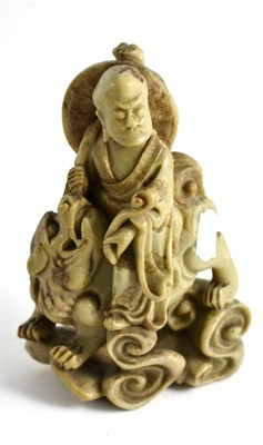 Lot 116 - A Chinese Soapstone Figure of a Scholar, 19th century, riding on the back of a lion dog, 22cm high