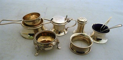 Lot 234 - Two silver napkin rings, silver tea strainer, silver salt, three piece silver cruet and three...