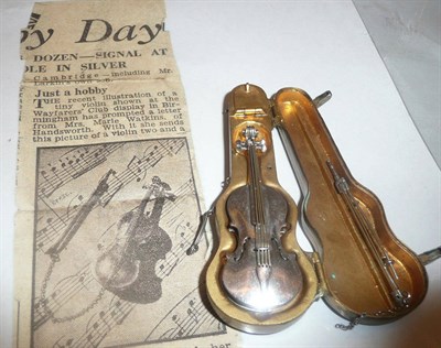 Lot 522 - Miniature white metal violin brooch stamped 'Silver' with bow, in a copper case with newspaper...