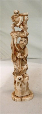 Lot 135 - A marine ivory one piece carving of a man stood on a rock with a man perched on his head, signature