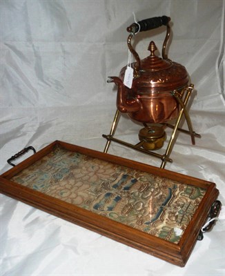 Lot 18 - Embroidered kimono sleeve set into a glazed two handled tray, copper kettle and brass stand (2)