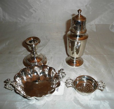 Lot 298 - A silver sugar caster, a tea strainer, a small two handled scalloped bowl and a loaded candlestick