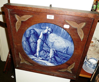 Lot 323 - Hand painted blue and white plaque of a woodcutter in an Arts and Crafts frame