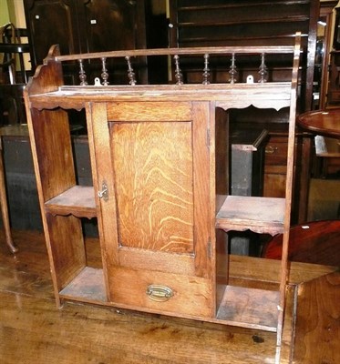 Lot 562 - An oak wall hanging shelf with cupboard and drawer to the centre