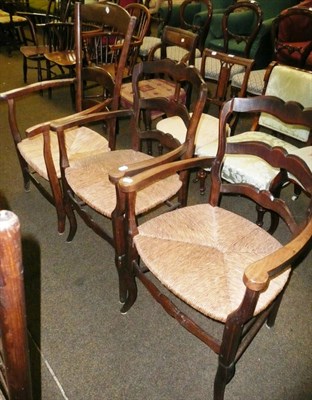 Lot 589 - A pair of French country style ladder back arm chairs with rush seats and another similar