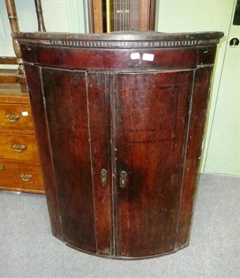 Lot 529 - A Georgian oak bow front hanging corner cupboard