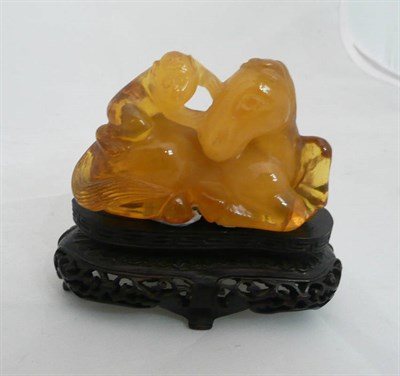 Lot 82 - A Chinese amber-type carving of a monkey on the back of a horse, on a carved and pierced wooden...