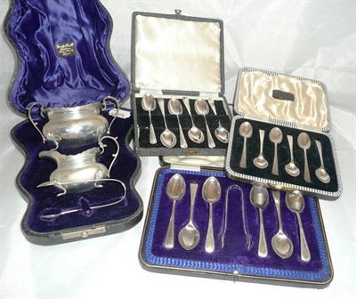 Lot 174 - A cased silver sugar basin, cream jug and sugar tongs and three cased sets of silver spoons