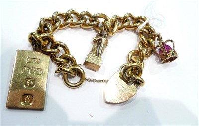 Lot 438 - A 9 carat gold curb and lock bracelet hung with an ingot and two charms