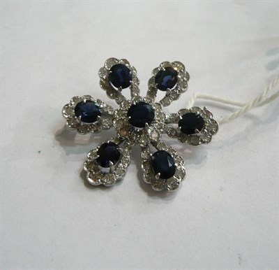 Lot 106 - A sapphire and diamond brooch, as a stylised flower, each petal set with a sapphire within a border