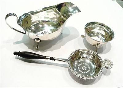 Lot 468 - A silver sauce boat, Birmingham 1934, a silver tea strainer and stand, Birmingham 1954