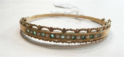 Lot 59 - A 9ct gold emerald and seed pearl bangle