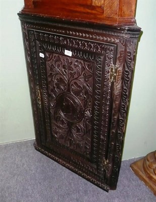 Lot 587 - A carved ebonised oak corner cupboard