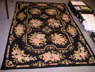 Lot 1040 - Large Woolwork Rug on a black ground decorated with flowers, 175 cms by 260 cms.