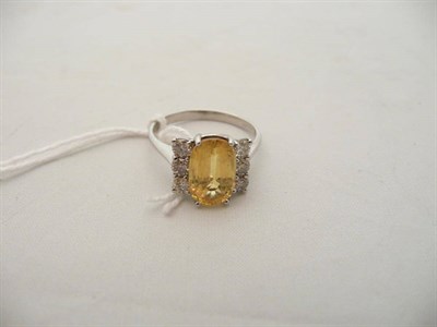 Lot 127 - A 14 carat white gold, yellow sapphire and diamond ring