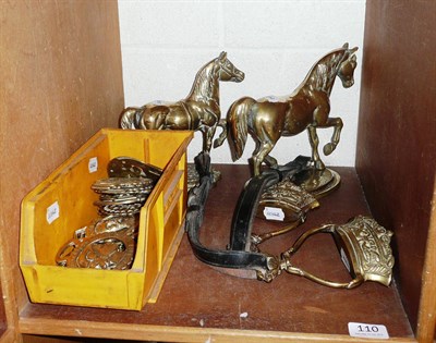 Lot 110 - Quantity of horse brasses, two brass horses and two straps on one shelf