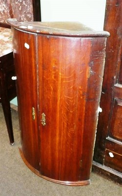 Lot 485 - A George III bow fronted hanging corner cupboard