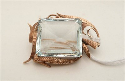 Lot 69 - An aquamarine brooch, a large step cut aquamarine claw set within a stylised leaf frame,...