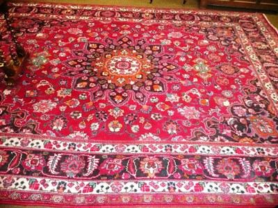 Lot 546 - West Persia village carpet, the raspberry field of scrolling floral vines around a central...