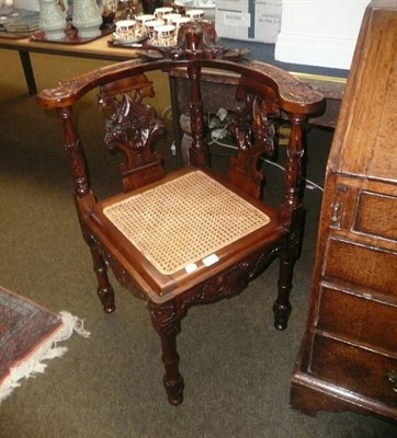 Lot 658 - An elaborately carved corner chair with cane drop-in seat