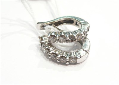 Lot 138 - A pair of diamond hoop earrings (one stone missing)