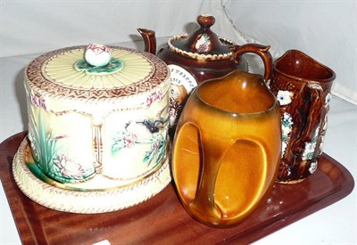 Lot 185 - A Measham teapot, water jug, Majolica cheese dome and a whiskey jug