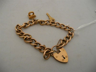 Lot 255 - A curb and lock bracelet stamped "9ct" with a 9ct gold key charm and a 9ct gold well charm,...