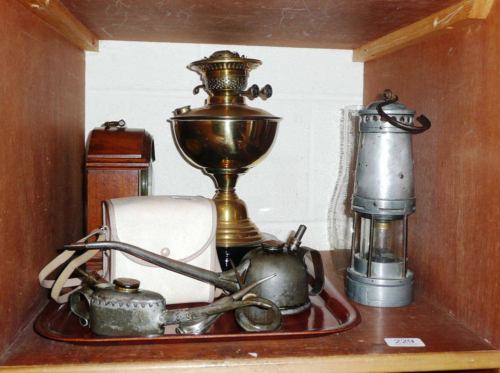 Lot 229 - A tray including an oil lamp, cased 'Brownie' camera, miner's lamp, oil cans and a mantel timepiece