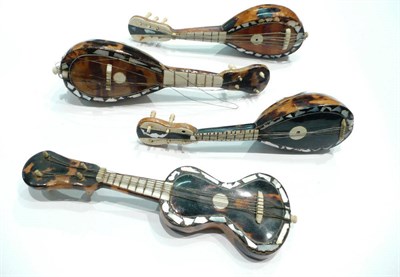 Lot 435 - Three tortoiseshell, bone and mother of pearl inlaid banjos and a similar guitar