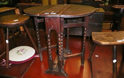 Lot 715 - A small oak drop leaf table and two 19th century three legged stools