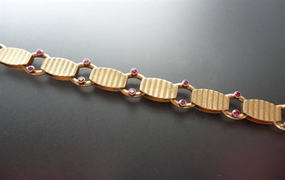 Lot 302 - An 18 Carat Gold Ruby Set Bracelet, grooved lozenge links are spaced by loops set with two...