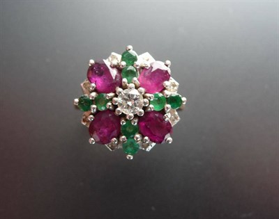 Lot 305 - A Ruby, Emerald and Diamond Cluster Ring, four oval cut rubies spaced by pairs of round cut...