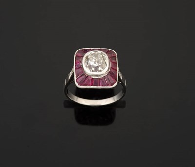 Lot 308 - A Diamond and Ruby Cluster Ring, an old cut diamond in a white rubover setting sits within a border