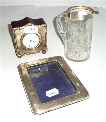 Lot 110 - A cut glass jug with silver rim, silver photograph frame and a small silver mounted timepiece