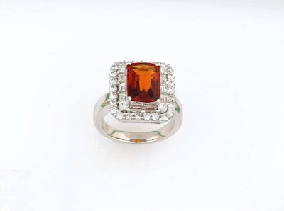 Lot 340 - A Garnet and Diamond Cluster Ring, the cushion cut deep orange coloured garnet is bordered by a row