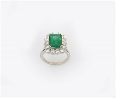 Lot 349 - An Emerald and Diamond Cluster Ring, the emerald-cut emerald in a four double corner white claw...