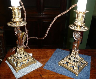 Lot 315 - A pair of gilt metal and bronze table lamps with red metal shades