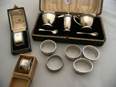 Lot 339 - A cased silver three piece cruet, seven napkin rings and a silver bookmark as a trowel