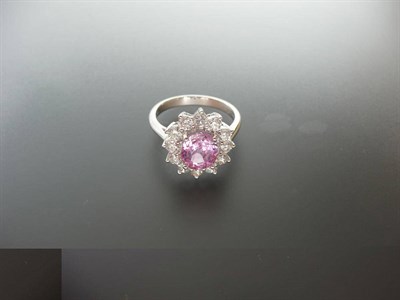 Lot 356 - A Pink Sapphire and Diamond Cluster Ring, the oval mixed cut pink sapphire bordered by round...