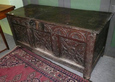 Lot 419 - A 17th century oak coffer with plank constructed top above a heavily carved front with lunette...