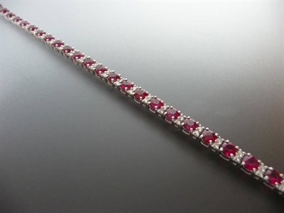 Lot 369 - A Ruby and Diamond Line Bracelet, round brilliant cut rubies are spaced by pairs of round brilliant