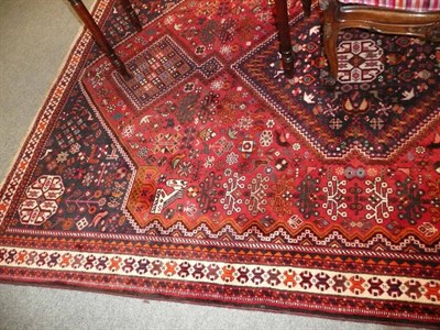 Lot 516 - A modern red ground fringed carpet with central blue lozenge