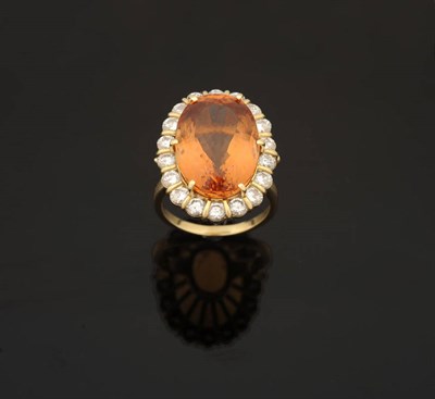 Lot 374 - A Topaz and Diamond Cluster Ring, the oval cut topaz sits above a row of round brilliant cut...