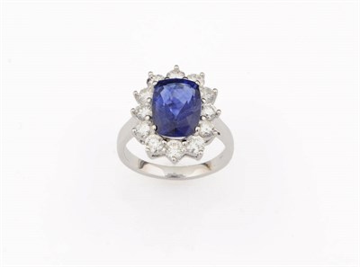 Lot 375 - A Sapphire and Diamond Cluster Ring, the cushion cut sapphire bordered by round brilliant cut...