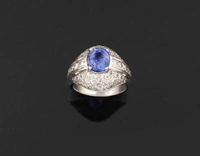 Lot 383 - A Sapphire and Diamond Bombé Ring, the oval mixed cut sapphire in a white claw setting sits...