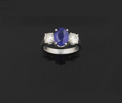 Lot 385 - A Sapphire and Diamond Three Stone Ring, the oval mixed cut sapphire sits between two round...