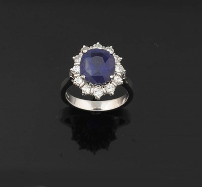 Lot 388 - An 18 Carat White Gold Sapphire and Diamond Cluster Ring, the oval mixed cut sapphire bordered...