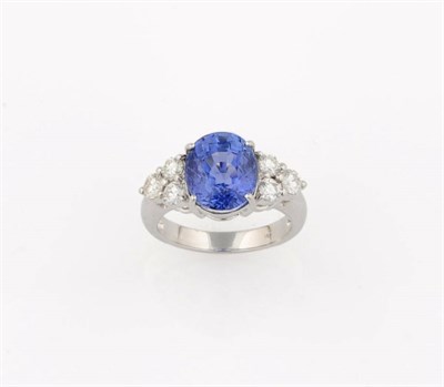 Lot 391 - A Sapphire and Diamond Ring, the cornflower blue oval mixed cut sapphire sits between a...