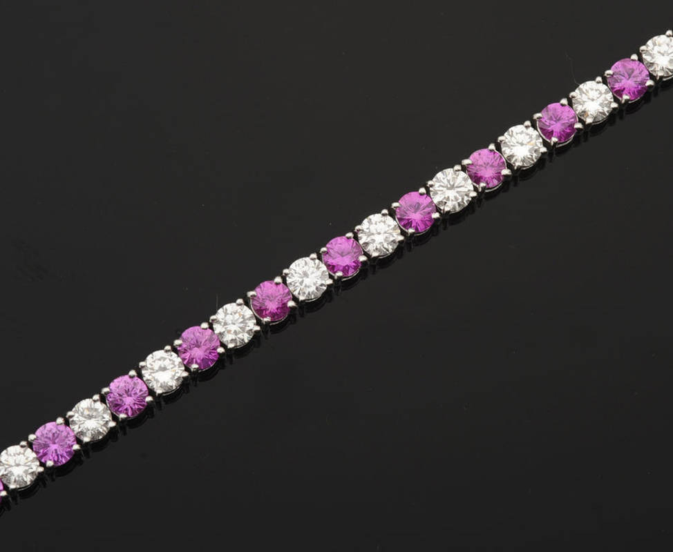 Lot 392 - A Pink Sapphire and Diamond Line Bracelet, round brilliant cut pink sapphires alternate with...